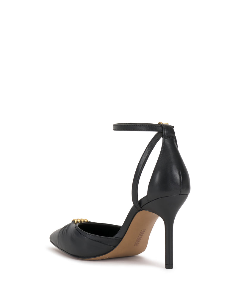 The Vince Camuto Mallie Pump is a black high-heeled shoe with a pointed toe, ankle strap, and gold buckle detail, shown from a rear side angle on a plain white background.