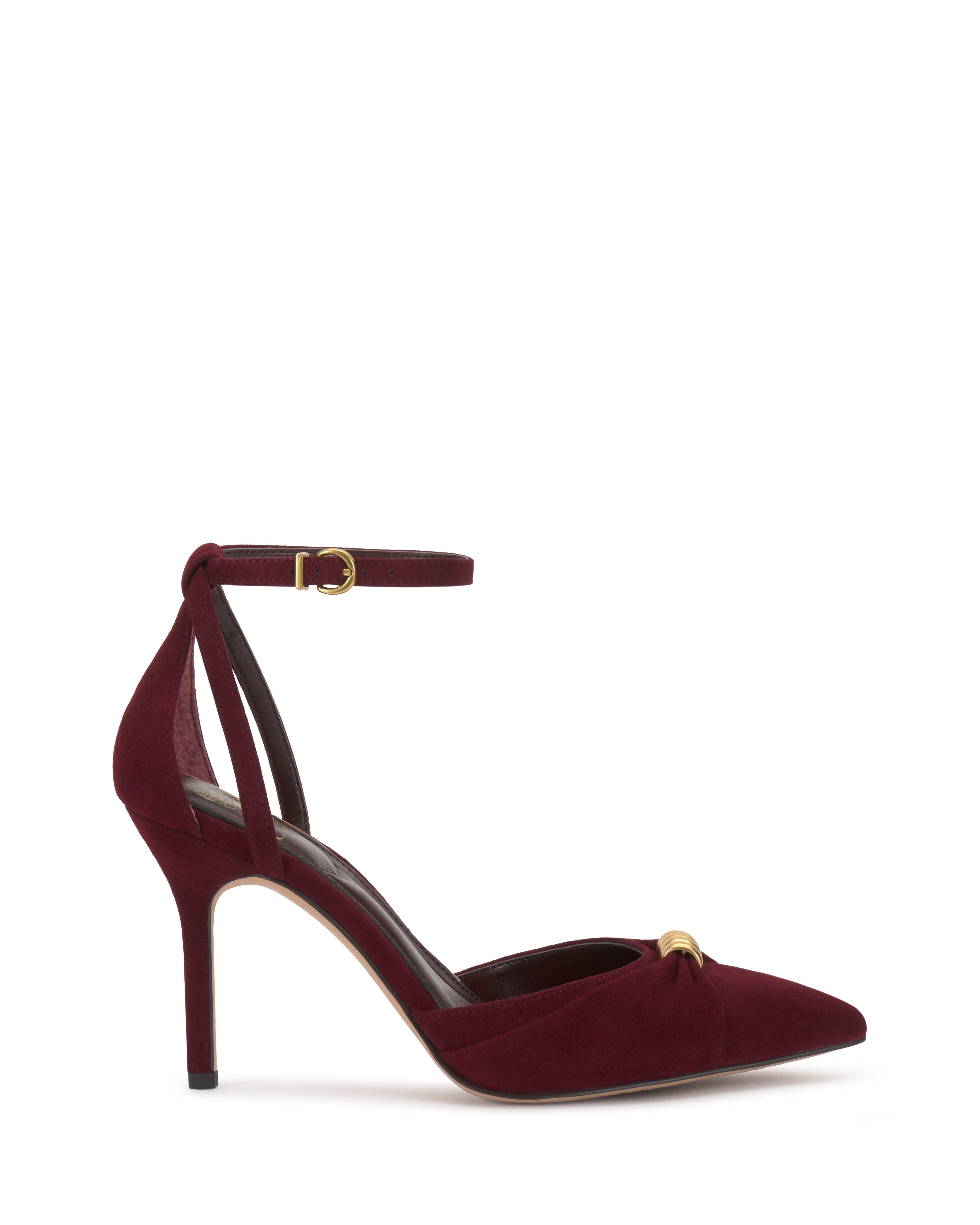 The Vince Camuto Mallie Pump is a burgundy suede high heel featuring a pointed toe, ankle strap with gold buckle, and a small gold embellishment on the front.