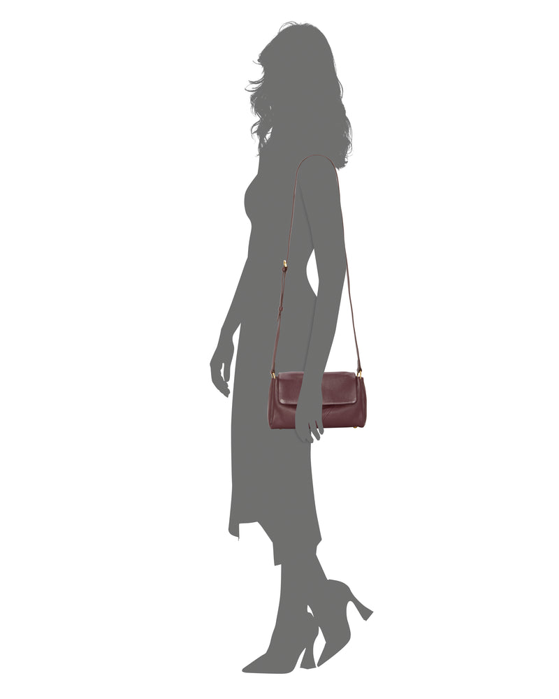 A woman in a mid-length dress and heels carries the Vince Camuto Medna Crossbody Bag with a long strap, shown against a white background.
