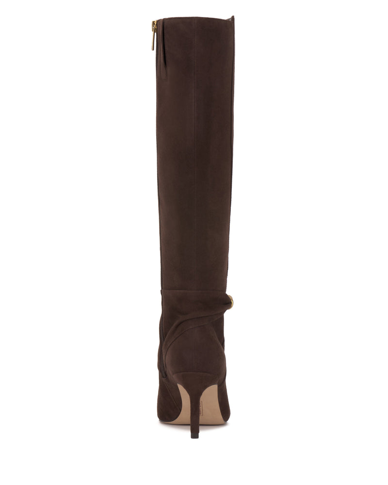 The Meezo Wide Calf Knee High Boot by Vince Camuto is a tall, dark brown suede knee-high boot with a pointed toe, mid-height skinny heel, side zipper, and a decorative strap with chic hardware at the ankle. Back view shown.