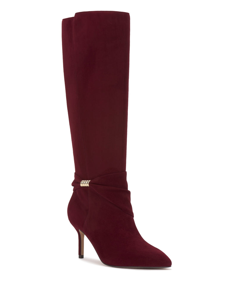 The Meezo Knee High Boot by Vince Camuto is a tall, burgundy suede boot with a pointed toe, skinny heel, and ankle wraparound detail accented by chic gold hardware.