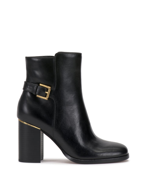 The Vince Camuto Melvani Bootie is a black leather ankle boot featuring a chunky high heel, rounded toe, and a decorative gold buckle on the outer side. Its sleek and elegant design embodies a modern, minimalist style.