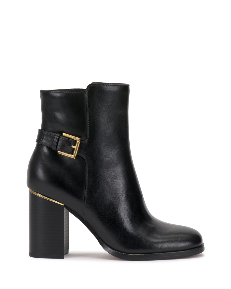 The Vince Camuto Melvani Bootie is a black leather ankle boot featuring a chunky high heel, rounded toe, and a decorative gold buckle on the outer side. Its sleek and elegant design embodies a modern, minimalist style.