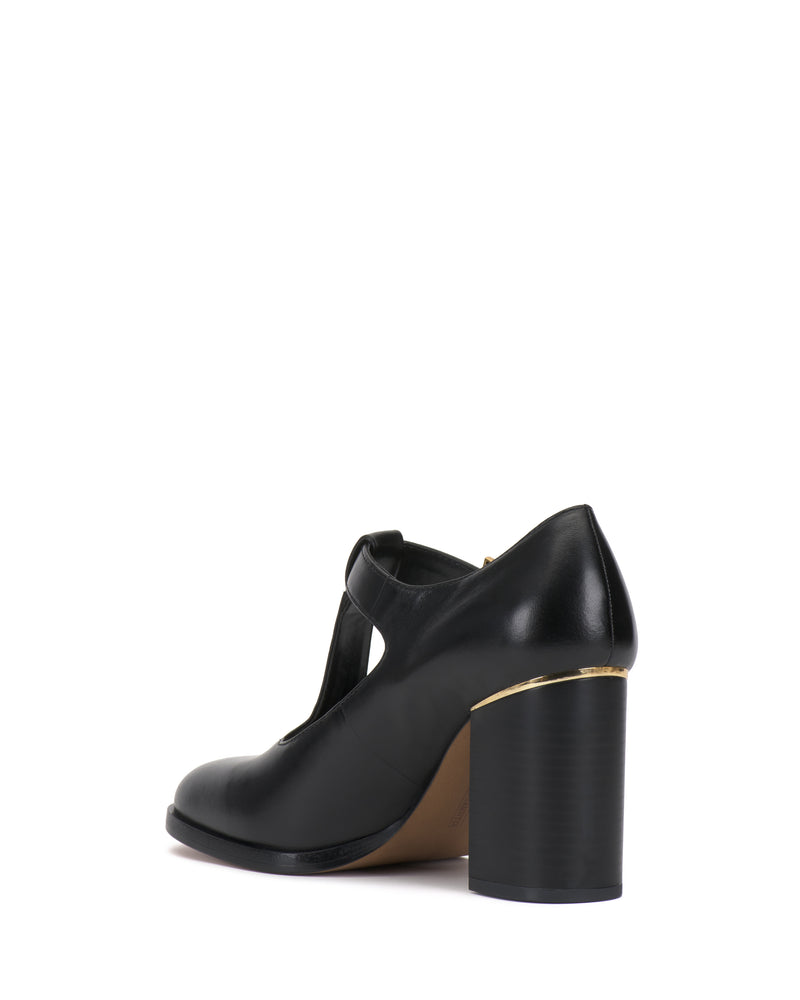 Vince Camuto Micha Pump in black, featuring a T-strap design, a thick block heel with gold-toned metal detailing at the base, and a touch of vintage charm.