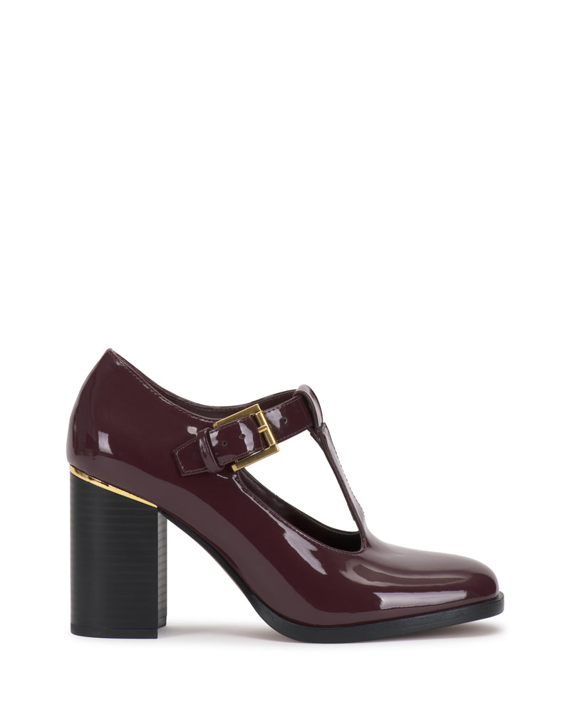 The Micha Pump by Vince Camuto features maroon patent leather in a T-strap design with a round toe, chunky high heel, and gold buckle detail, exuding vintage charm and feminine style. It is shown in profile against a white background.