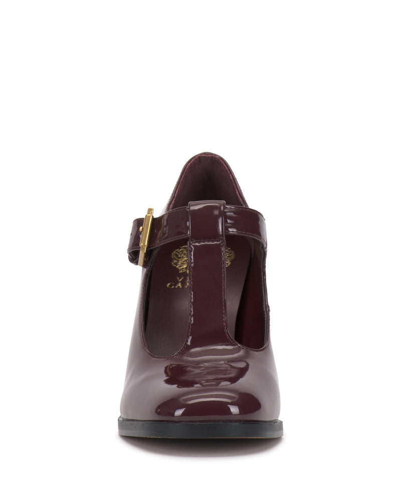 Front view of the Micha Pump by Vince Camuto, featuring shiny burgundy patent leather in a T-strap design with a gold buckle, exuding vintage charm and feminine style, displayed against a white background.
