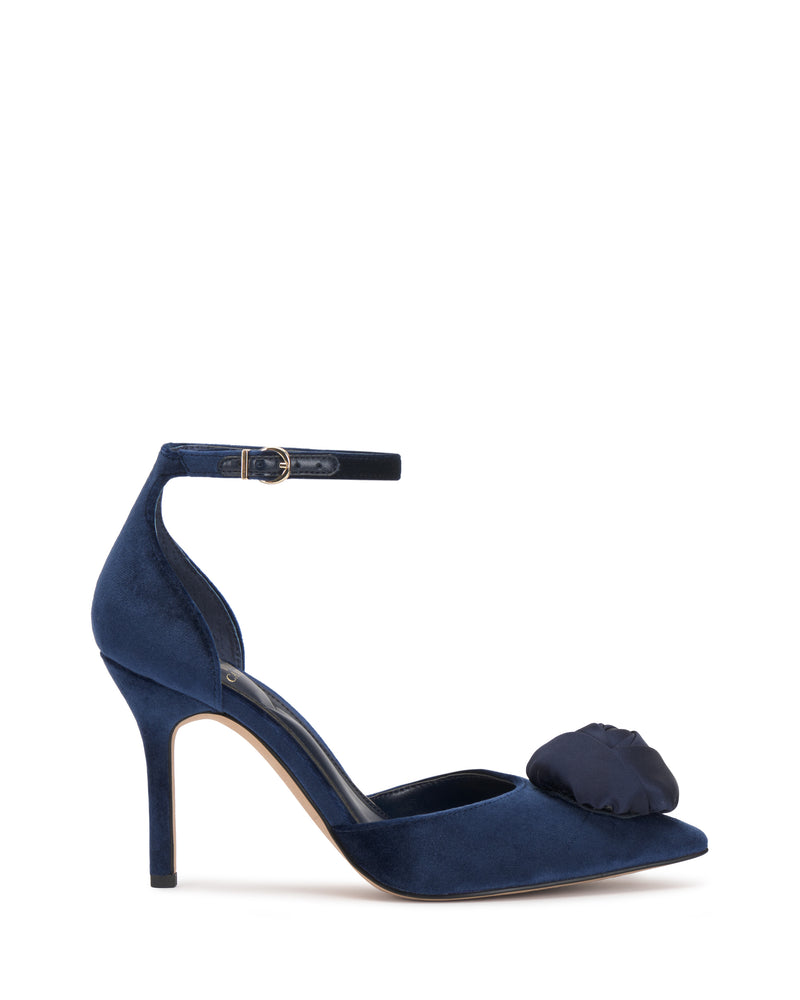 The Vince Camuto Mirezzo Pump is a navy blue suede stiletto with an ankle strap and a bow on the toe, shown against a plain white background.