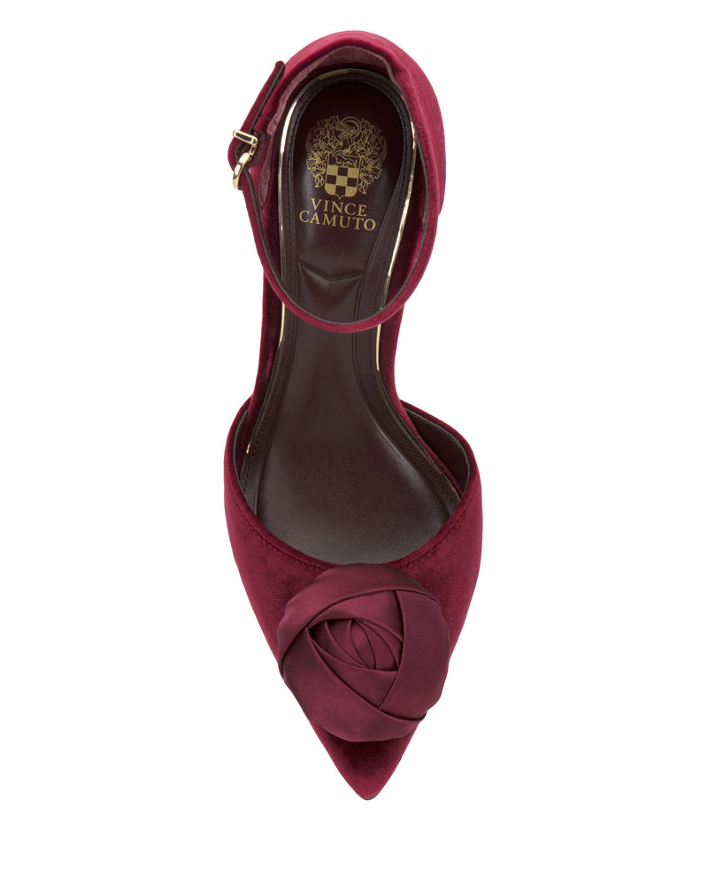 The Mirezzo Pump by Vince Camuto features a burgundy pointed toe, ankle strap, decorative rose on the toe, and a gold Vince Camuto logo on the insole.