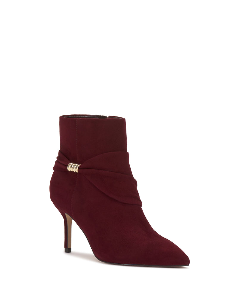 The Murlea Bootie by Vince Camuto is a burgundy suede ankle boot featuring a pointed toe, slim high heel, and a stylish wrap detail with a gold side accent.