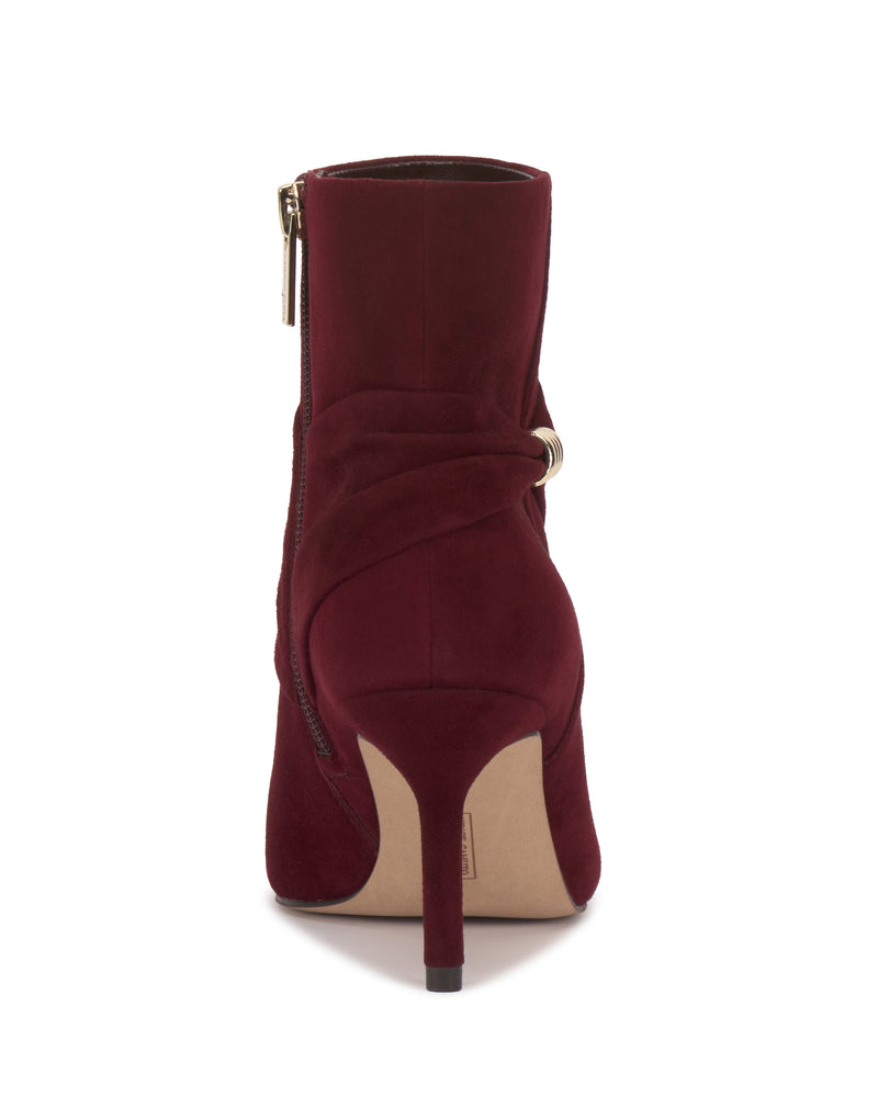 The Murlea Bootie by Vince Camuto is a burgundy suede ankle boot with high heels, a back zipper, wrapped ankle detailing, and a gold accent.