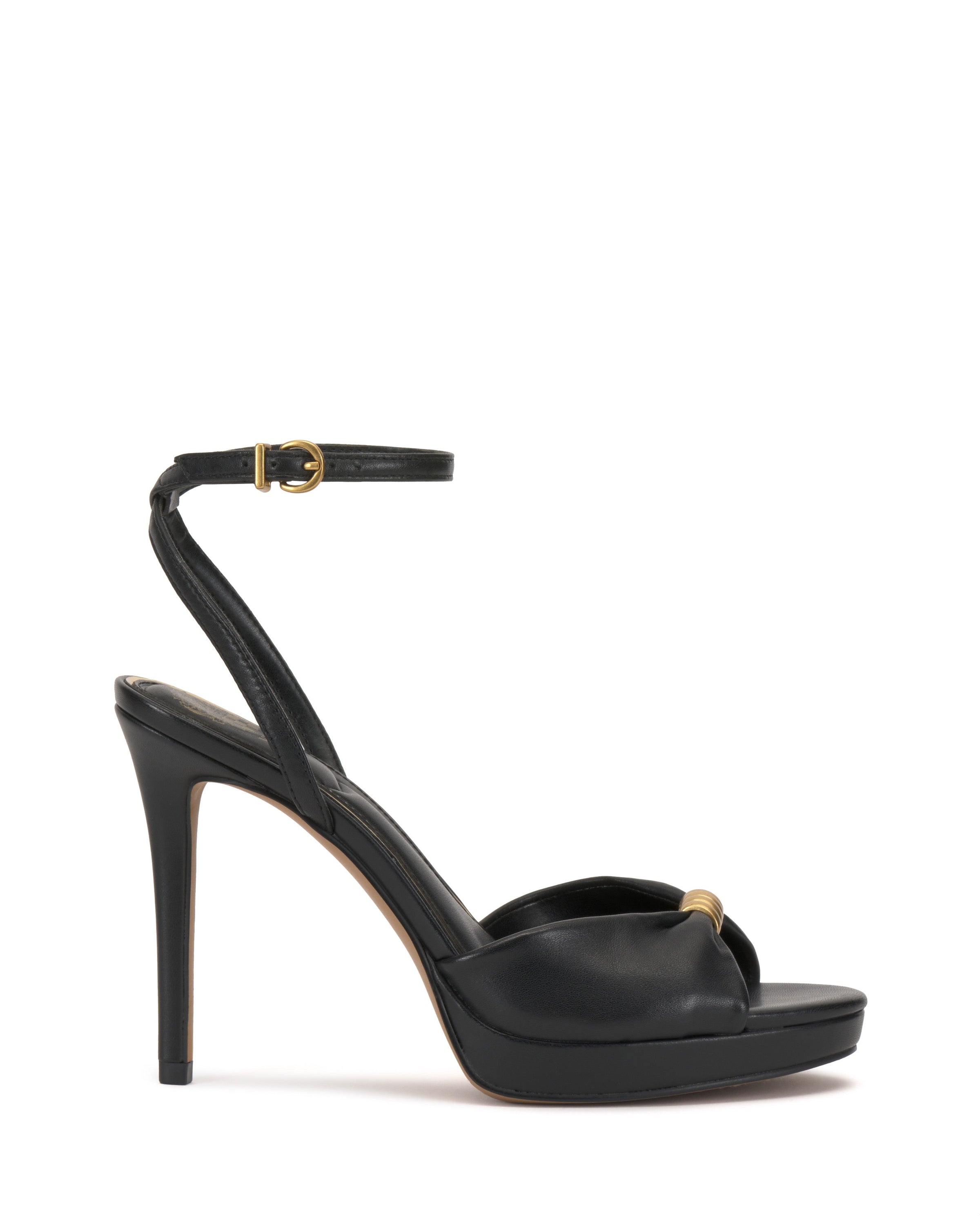 The Vince Camuto Neala Sandal is a black high-heeled shoe with a skinny ankle strap and gold buckle, peep toe, gold accent on the front strap, slim tall heel, and a slight platform for an elegant touch.