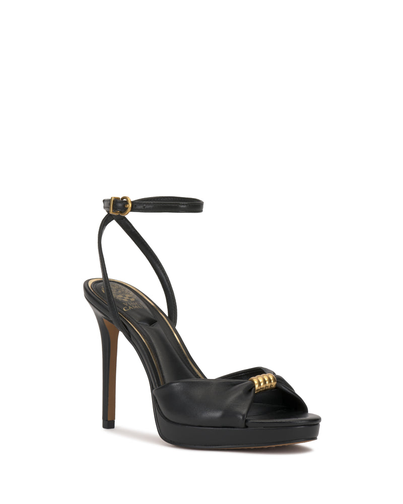 The Vince Camuto Neala Sandal is a black high-heeled sandal with an ankle strap, open toe, and gold-accented front strap, shown on a white background.