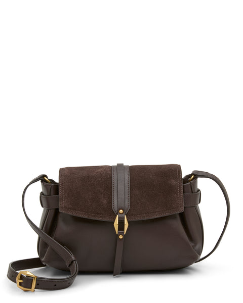 The Vince Camuto Nelly Crossbody Bag in dark brown leather features a suede flap, gold buckle detail, and an adjustable strap. Displayed against a plain white background, this stylish accessory is the perfect complement to any outfit.