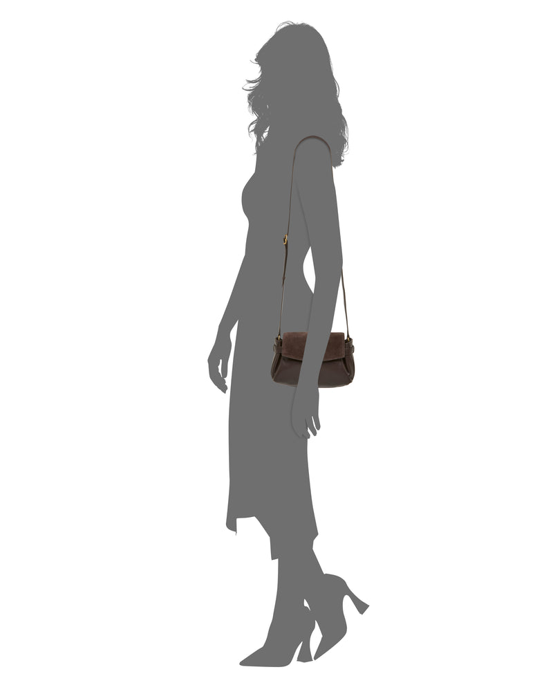 Silhouette of a woman in a dress and heels with the Vince Camuto Nelly Crossbody Bag in dark brown, standing against a white background—a striking statement of elegance and the perfect fashion accessory.