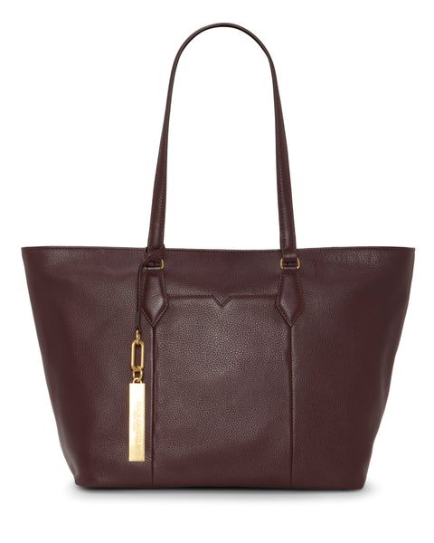 The Vince Camuto Noemi Tote Bag is a large, dark brown leather tote with two long shoulder straps and a gold rectangular tag. Its minimalist design features minimal stitching for a classic, elegant look.