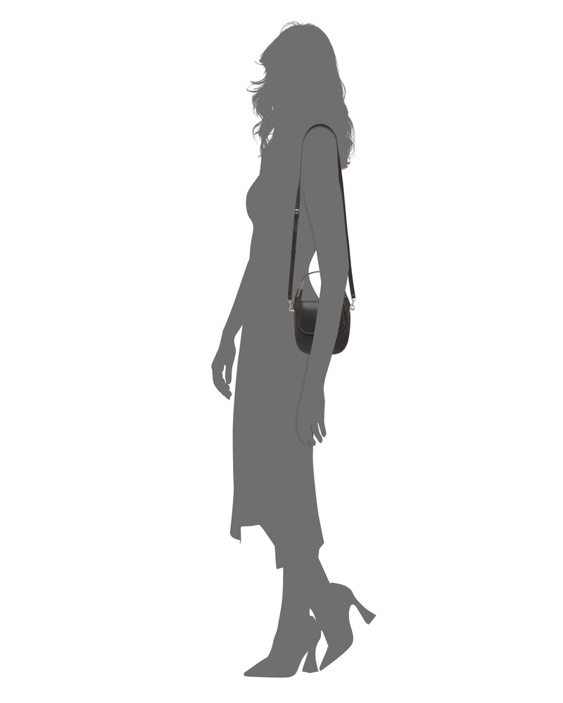 Silhouette of a woman in a dress and heels, standing sideways, carrying the Vince Camuto Noli Crossbody Bag.