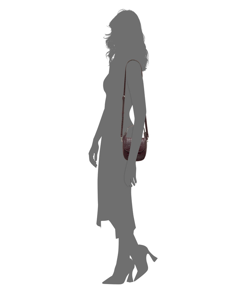 Silhouette of a woman wearing a calf-length dress and high heels, carrying the Vince Camuto Noli Crossbody Bag—a small, textured bag with a long strap.