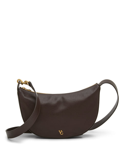 The Vince Camuto Orlie Crossbody Bag is crafted from dark brown leather in a curved silhouette, featuring a gold zipper, matching adjustable strap, and a small gold VC logo on the front. Showcasing high-quality craftsmanship, this modern accessory is photographed on a white background.