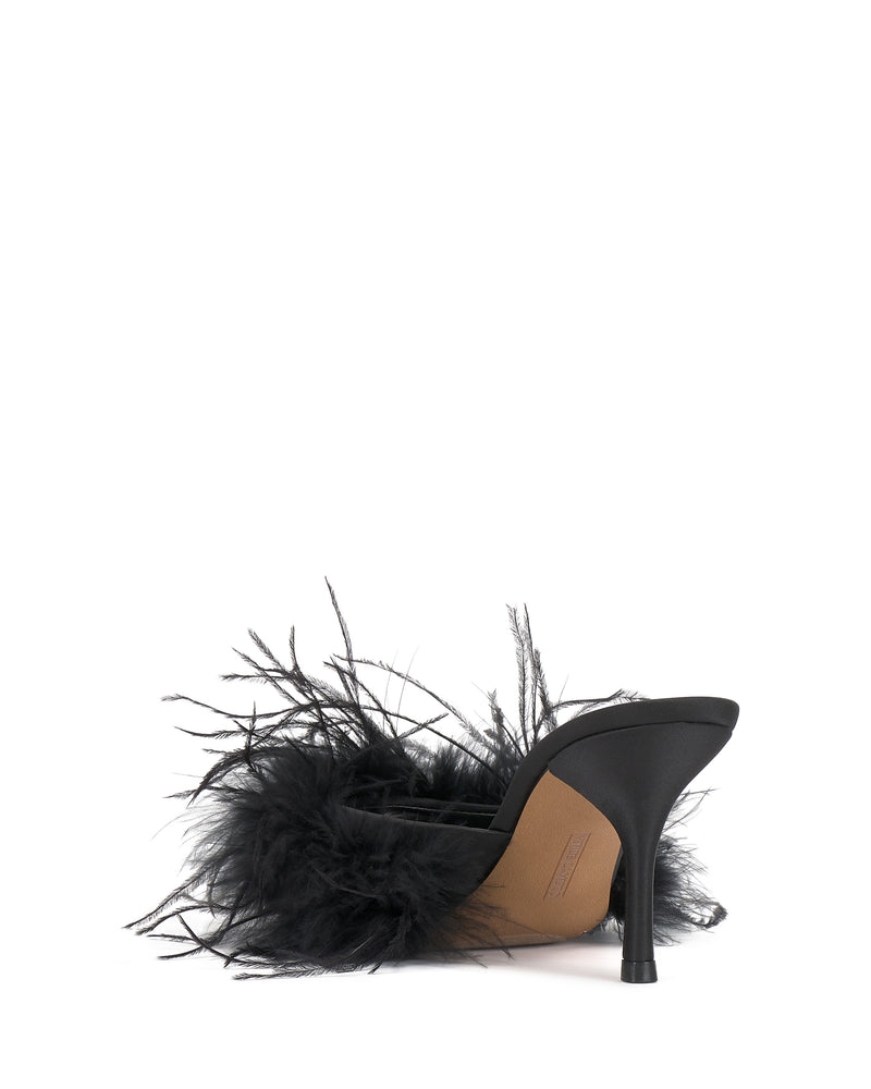 The Paelly Feather Mule by Vince Camuto features a black stiletto heel, tan suede upper, and black feather trim, shown from the back against a white background.