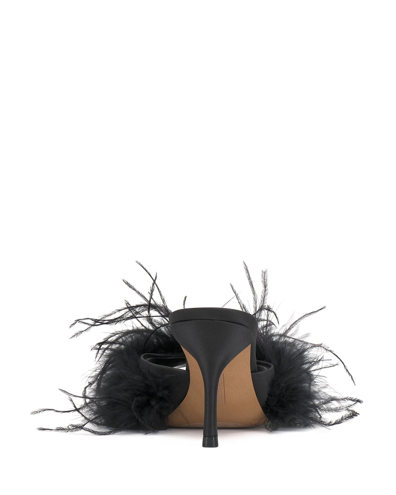 The Vince Camuto Paelly Feather Mule, a black high-heeled shoe with a fluffy feather trim, is shown from the back against a white background.