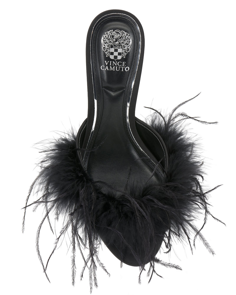 The Vince Camuto Paelly Feather Mule is a black slide sandal with a fluffy feathered trim on the front strap, viewed from above. The insole displays the Vince Camuto logo in white.
