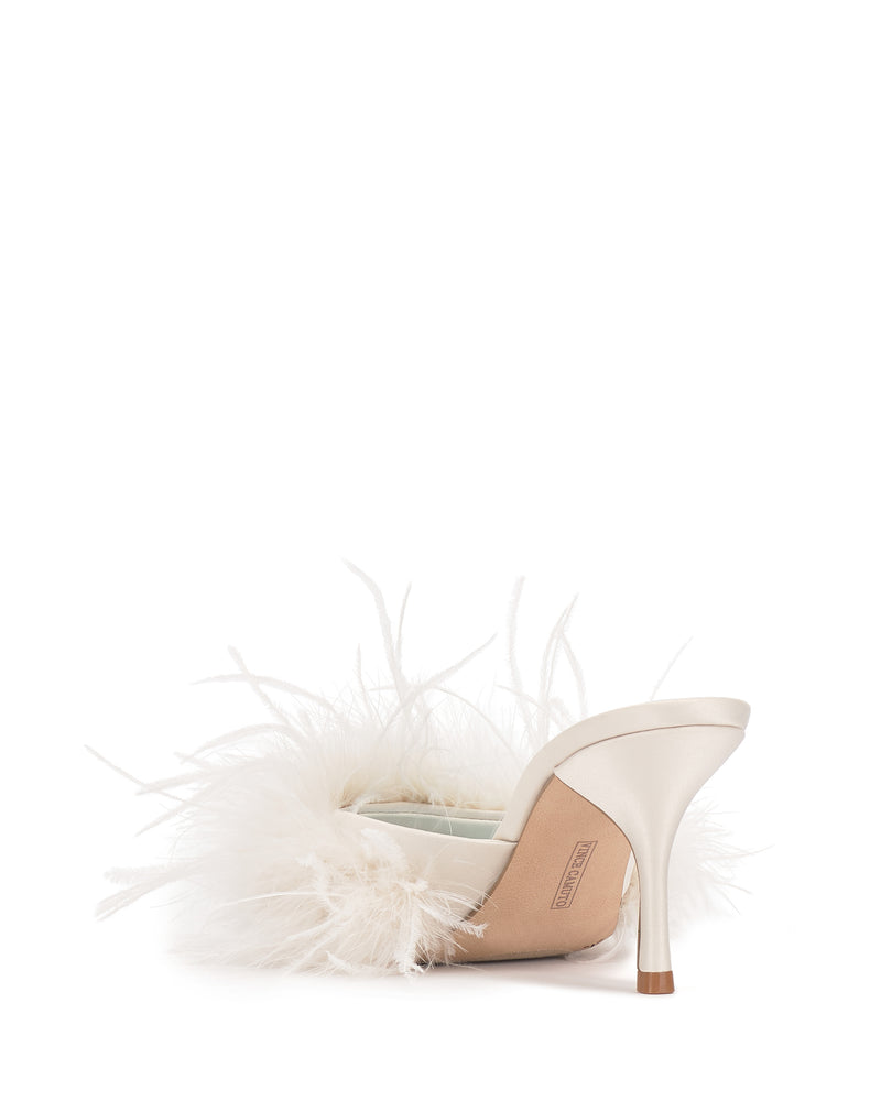 The Vince Camuto Paelly Feather Mule features a satin finish in beige and white, adorned with soft white feathers, and is pictured from the back against a white background.