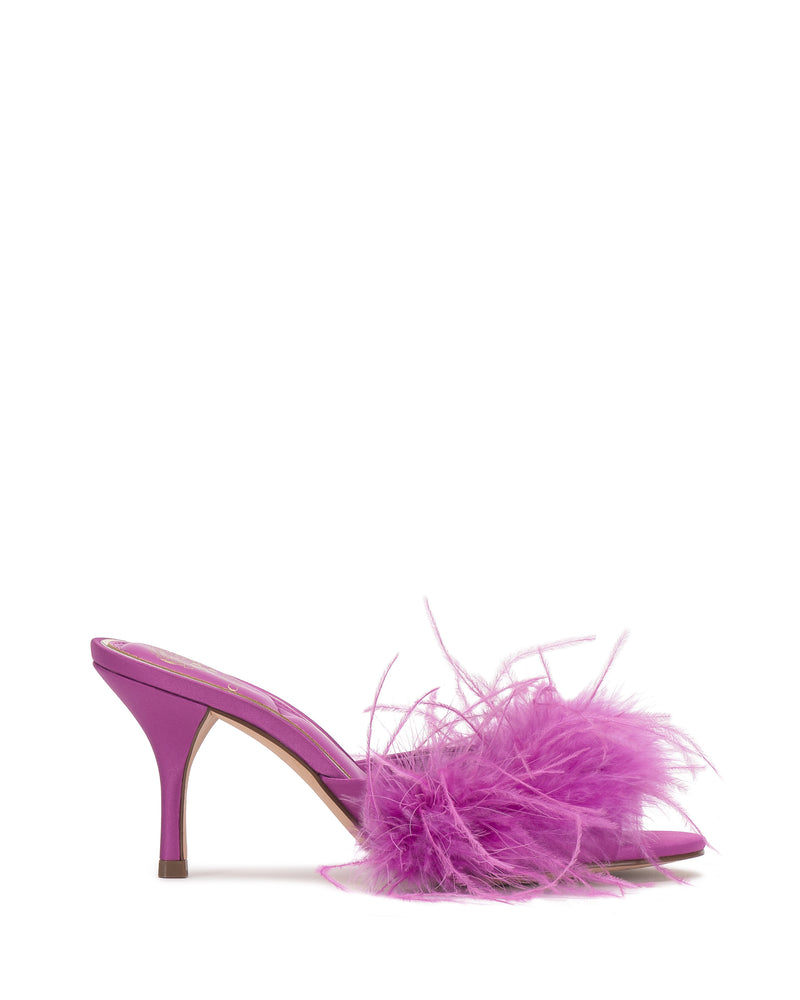 The Paelly Feather Mule by Vince Camuto is a bright magenta heeled sandal featuring a pointed toe, fluffy matching feathers on the front strap, and a slender mid-height heel.