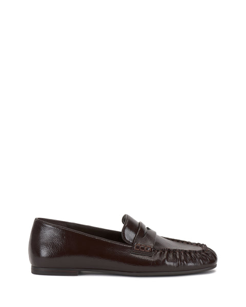 The Vince Camuto Paelyn Penny Loafer is a dark brown leather slip-on with a textured moccasin-style toe and low heel, shown in side profile against a white background.