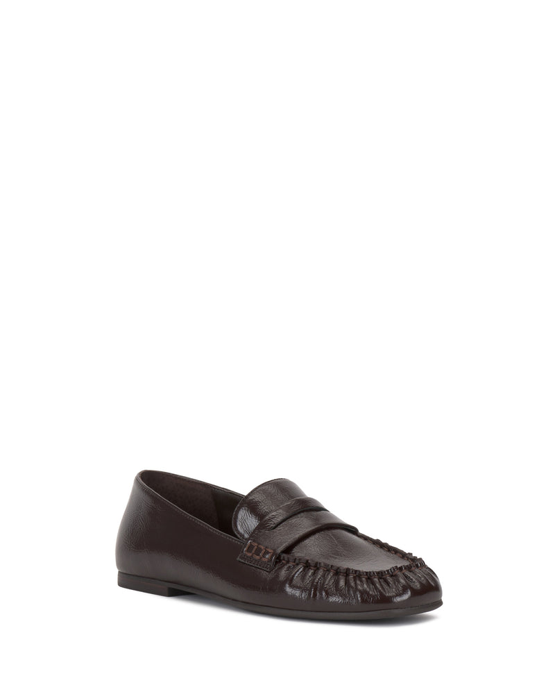 The Vince Camuto Paelyn Penny Loafer is a single dark brown, moccasin-inspired shoe featuring a stitched toe, low heel, and classic penny slot detail, shown against a plain white background.