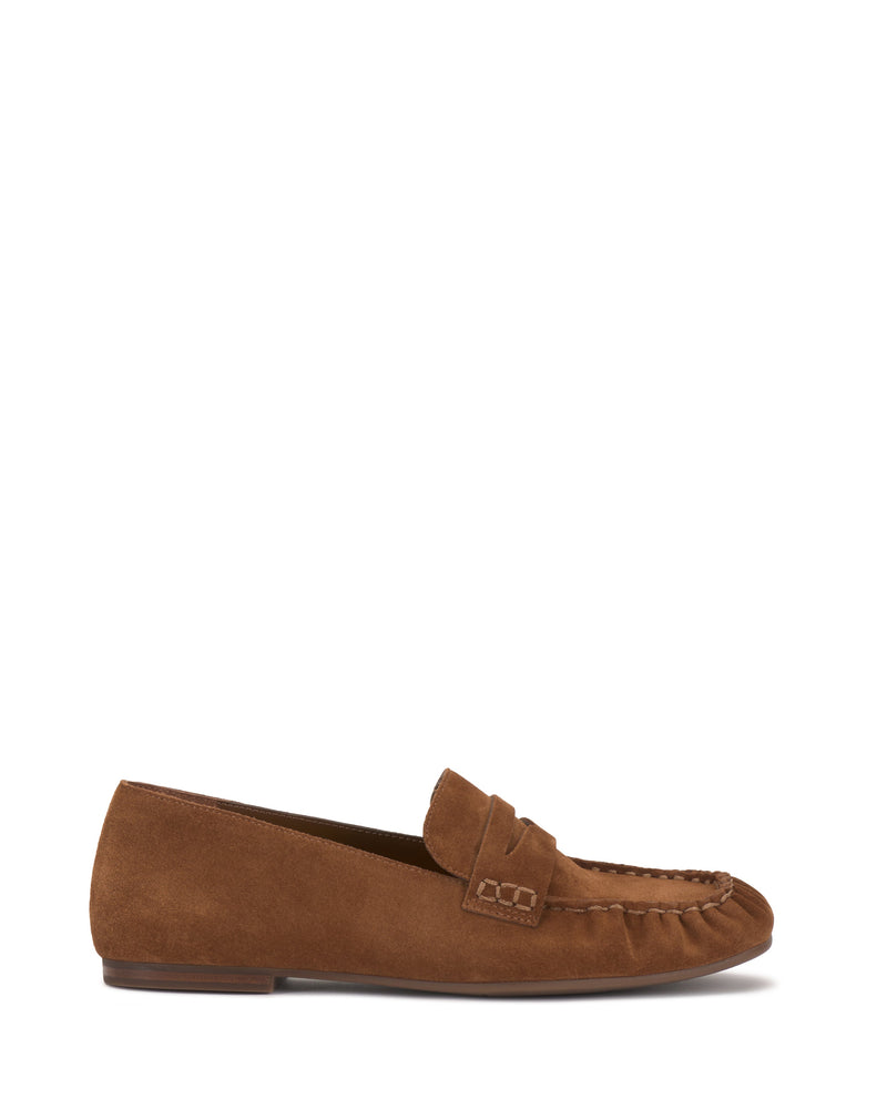The Vince Camuto Paelyn Penny Loafer is a brown suede slip-on with visible stitching, a low heel, and classic moccasin-inspired design, shown in side profile on a white background.