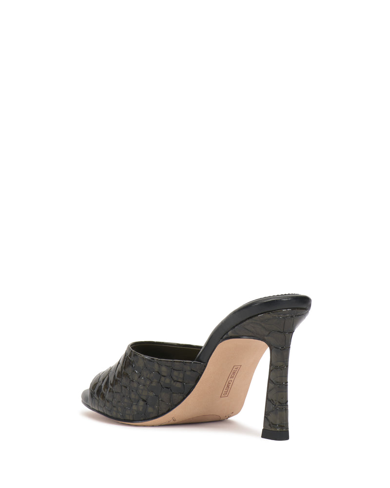 The Paigely Mule by Vince Camuto is a high-heeled, minimalist mule with a dark green woven texture, flared heel, open toe, and beige sole. Shown from the back on white, it features a pillow footbed for extra comfort.