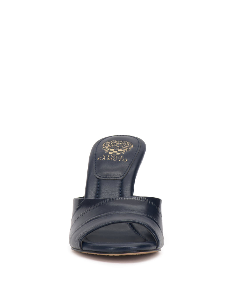 Front view of the Vince Camuto Paigely Mule in navy blue, featuring an open toe, crisscross strap design, flared heel, and a gold Vince Camuto logo on the insole, set against a white background.