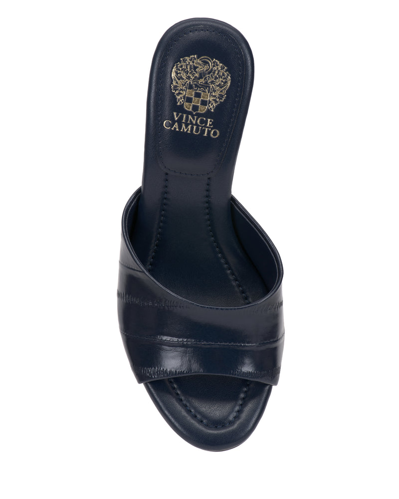 Top view of the Vince Camuto Paigely Mule in navy blue, showcasing a minimalist design with a wide strap and open toe. The insole features the Vince Camuto logo and crest in gold, and is designed with a pillow footbed for enhanced comfort.