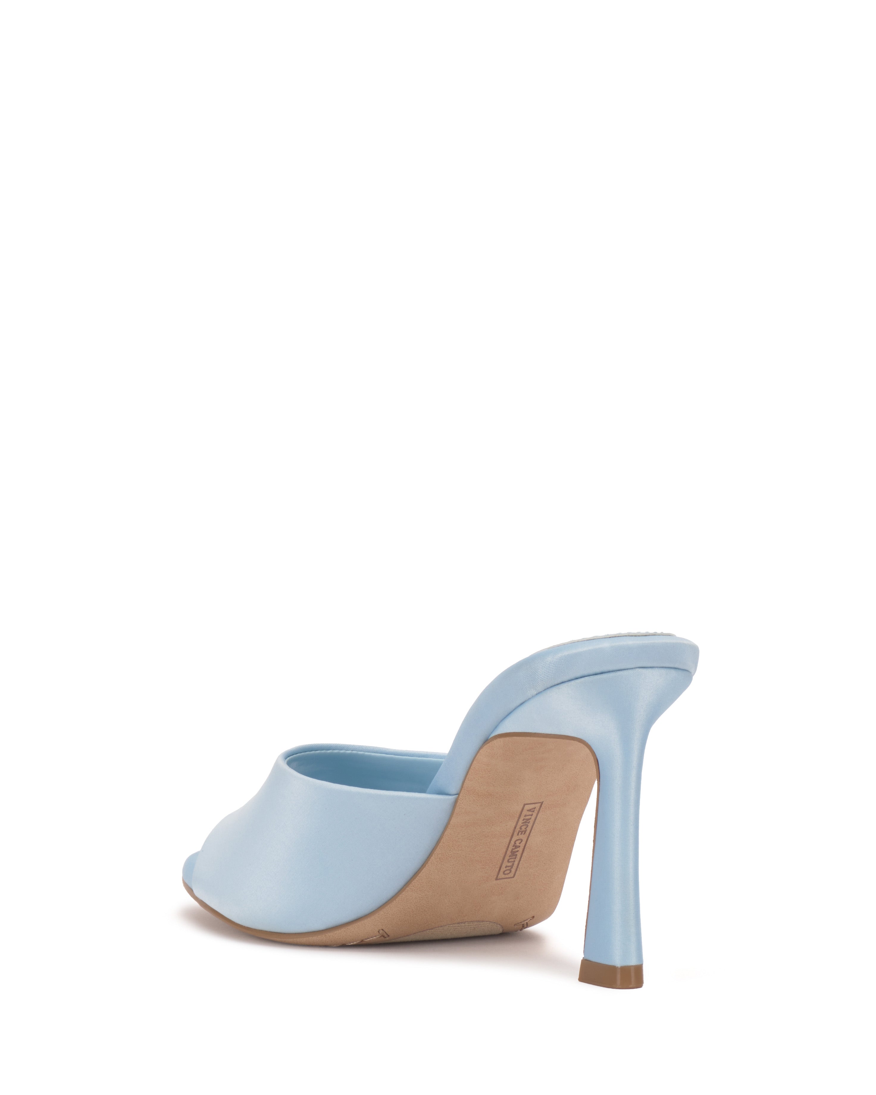 The Paigely Mule by Vince Camuto is a light blue minimalist mule featuring an open toe and a curved, flared stiletto heel, displayed from the back on a white background.