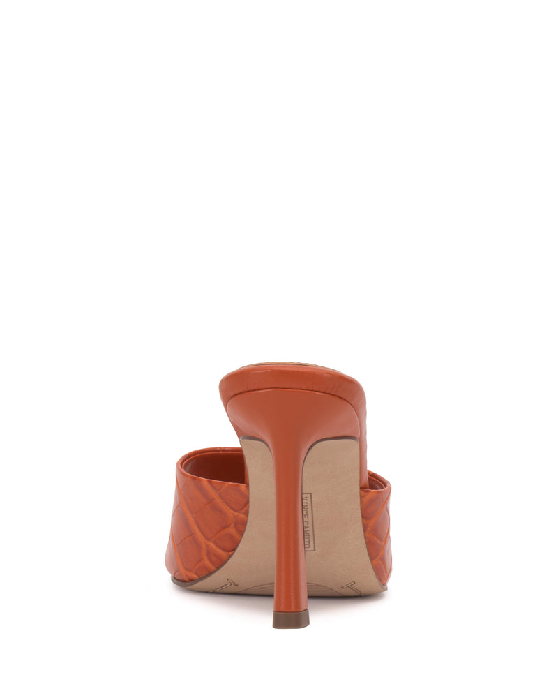 The Paigely Mule by Vince Camuto is an orange quilted minimalist mule shown from the back, highlighting its flared heel and a partial view of the padded upper.