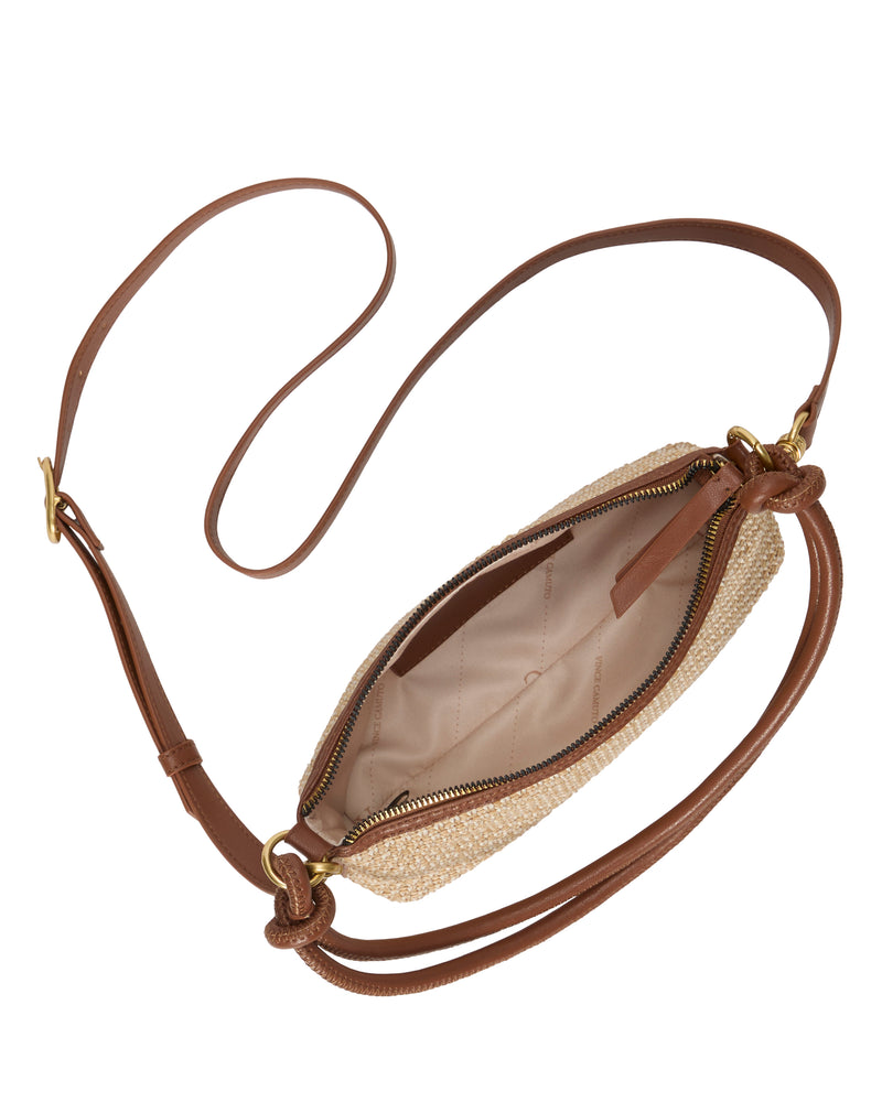 The Vince Camuto Paula Crossbody Bag features a long brown leather strap, gold hardware, and a beige fabric-lined interior with pockets, shown from above with its zipper open.