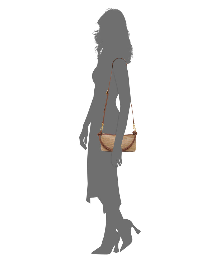 A woman in profile, wearing a dress and heels, carries the Vince Camuto Paula Crossbody Bag in beige and brown on her shoulder against a plain white background.