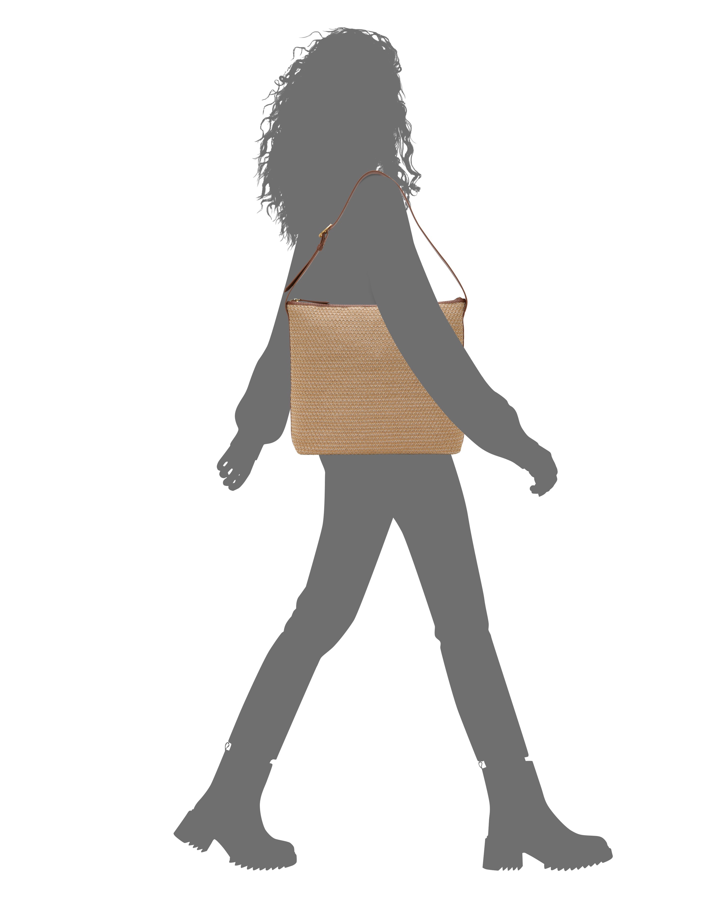 A person with curly hair, shown in profile against a white background, walks while carrying the Vince Camuto Paula Shoulder Bag—a tan woven style with brown straps—paired with boots for a perfect summer look.