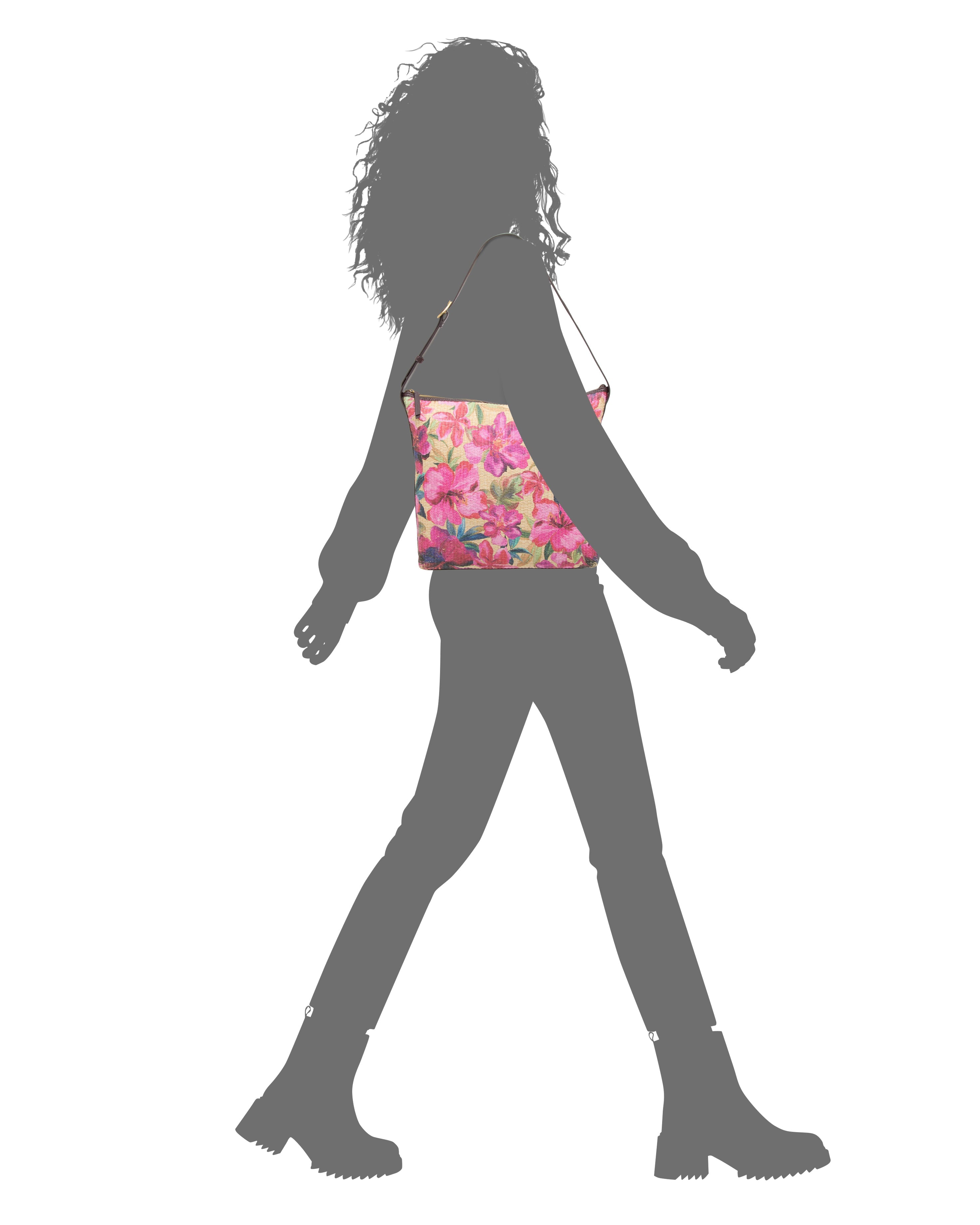 Silhouette of a person walking in boots, carrying the Vince Camuto Paula Shoulder Bag with a bright pink floral pattern—ideal for summer essentials—set against a white background.