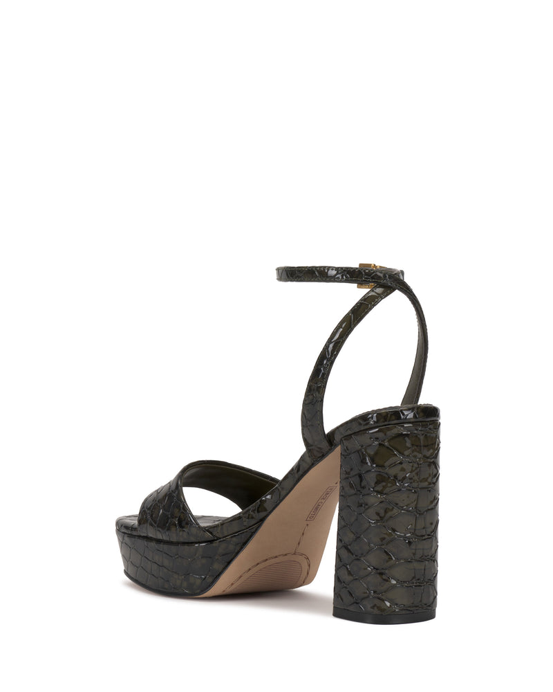 The Pendry Platform Sandal by Vince Camuto features a chunky block heel, ankle strap, and dark glossy crocodile texture, evoking retro 70s style with its bold platform silhouette.