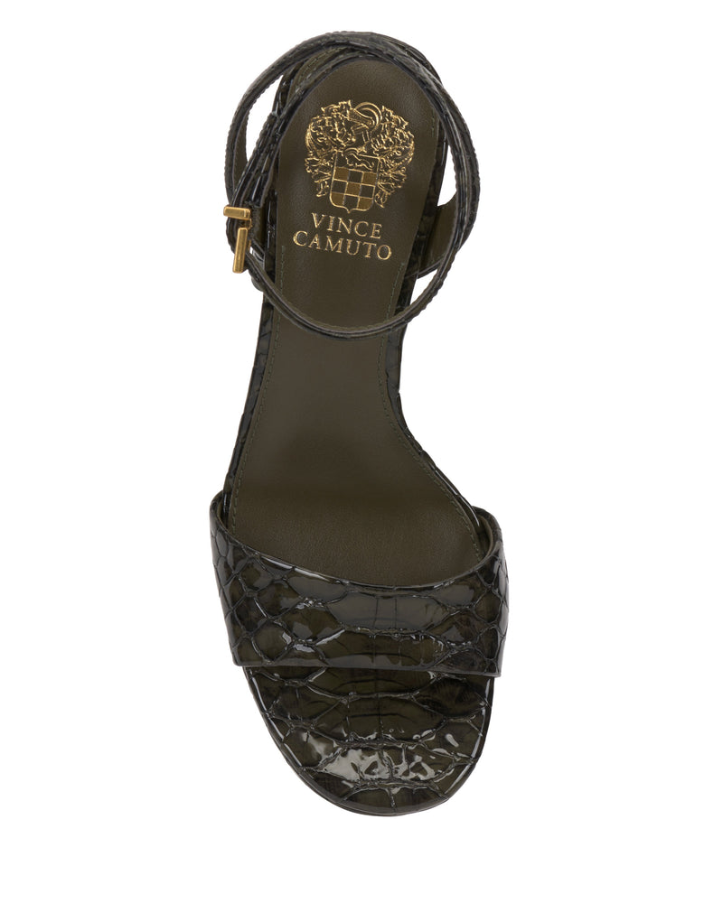 The Vince Camuto Pendry Platform Sandal is a black, crocodile-textured, open-toe heel with an ankle strap and gold buckle, featuring subtle ’70s style and the Vince Camuto logo in gold on the insole.