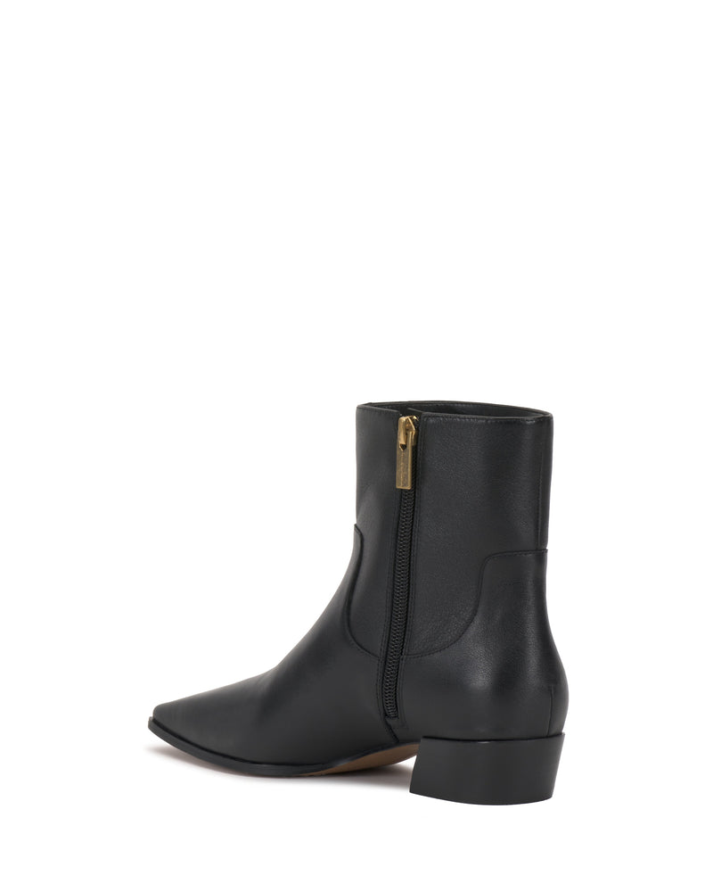 The Pertula Bootie by Vince Camuto is a black, pointed toe ankle bootie featuring a low block heel and a side zipper with a gold pull, shown against a white background.