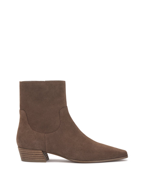 The Pertula Bootie by Vince Camuto features rich brown suede in a pointed-toe ankle silhouette with a low block heel and subtle stitching details. Styled in side profile against a white background, this design exemplifies refined style with modern simplicity.