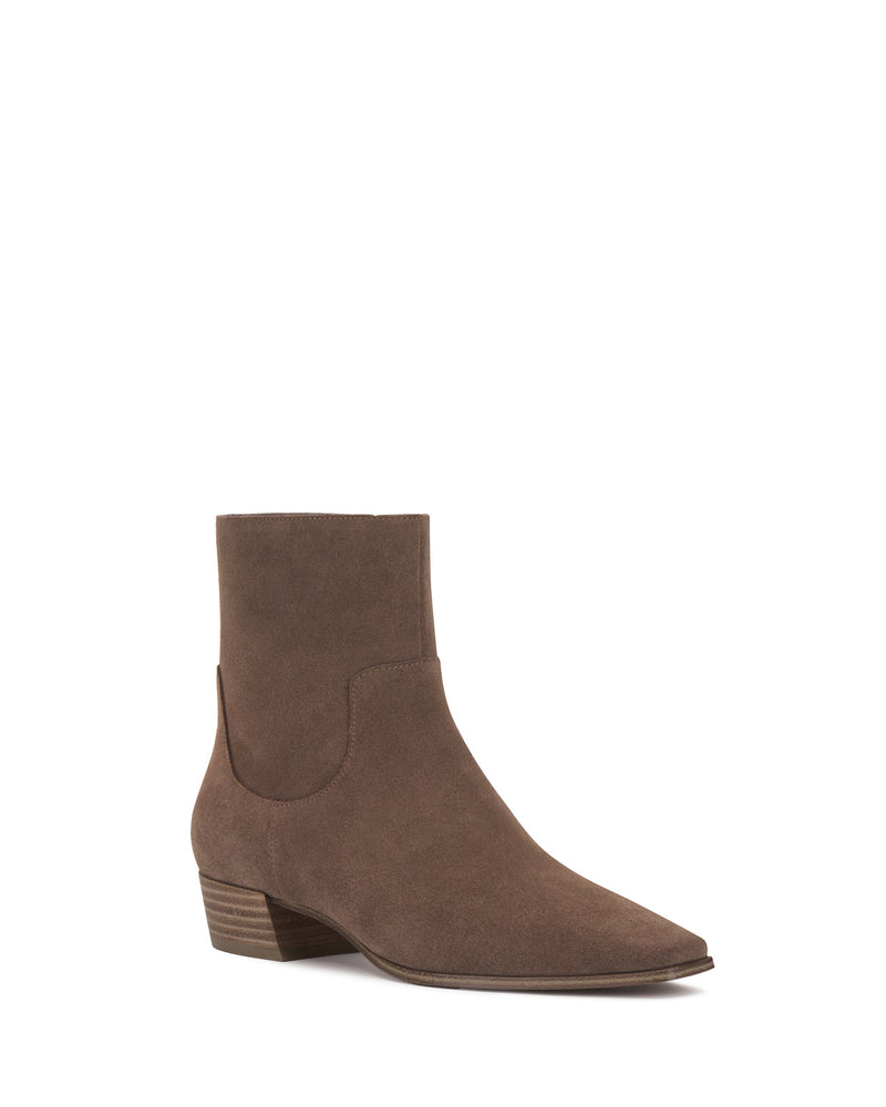 The Vince Camuto Pertula Bootie is a brown suede ankle bootie with a pointed toe, low block heel, and minimal stitching, shown on a white background.