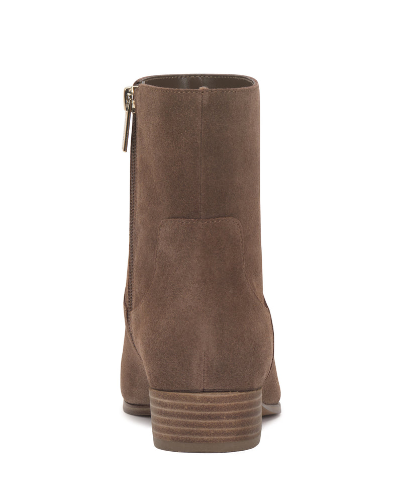 The Pertula Bootie by Vince Camuto is shown in brown suede from the back, highlighting a low stacked heel and a visible side zipper on the left. This stylish ankle bootie pairs classic elements with modern comfort, creating an effortlessly chic pointed toe silhouette.