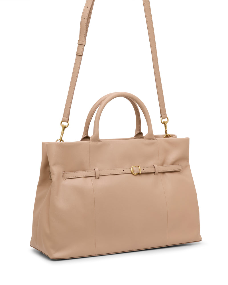 The Vince Camuto Rilah Satchel Bag is a beige leather handbag featuring dual handles, a detachable shoulder strap, gold-tone hardware, and a slim decorative belt detail across the front.