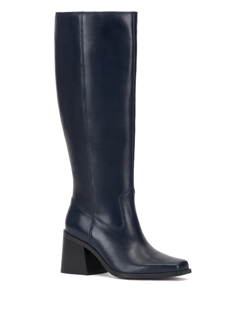 The Sangeti Boot by Vince Camuto is a single tall knee-high boot in navy blue leather, featuring a block heel and a slightly pointed toe, available in multiple calf widths and shown on a white background.