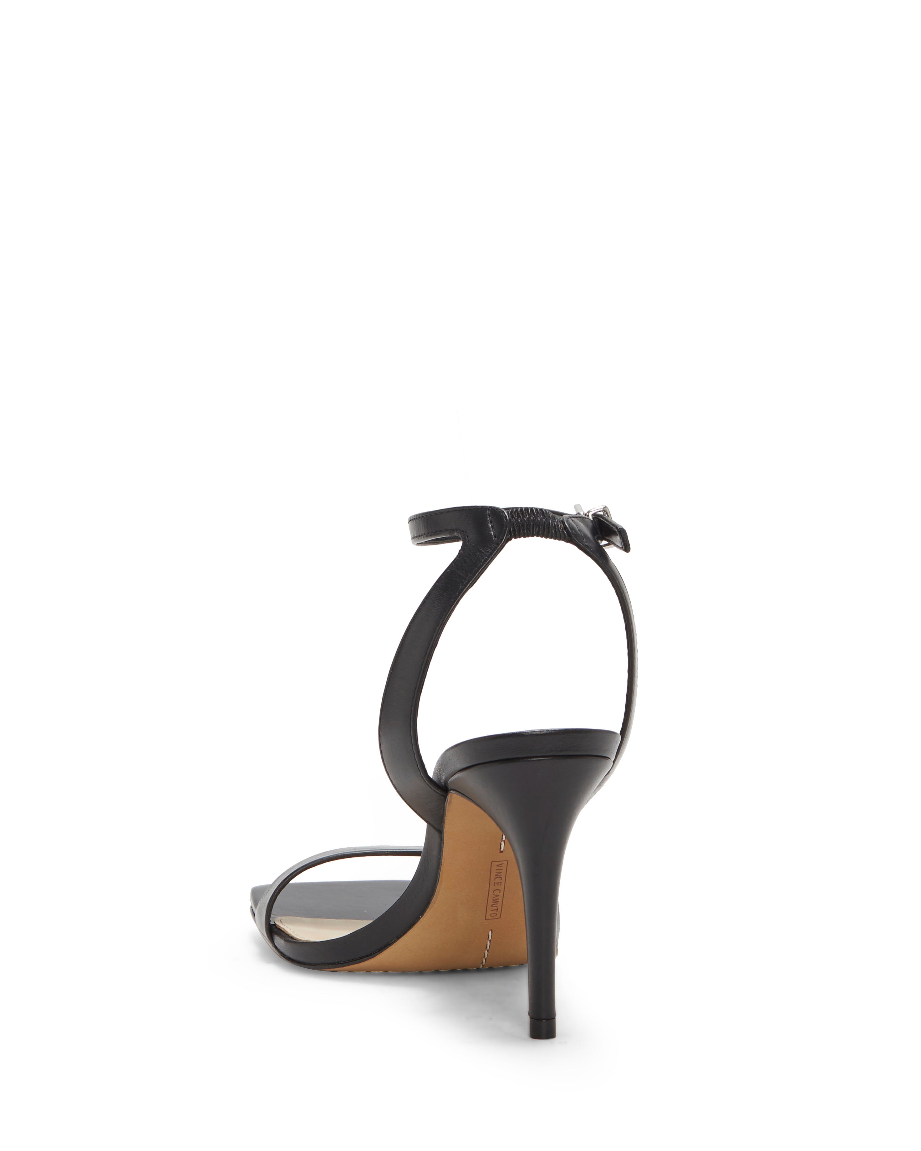 The Vince Camuto Saprenda Sandal is a black heeled sandal with a thin ankle strap and buckle, low tapered heel, light-colored insole, and tan outsole, viewed from the back.