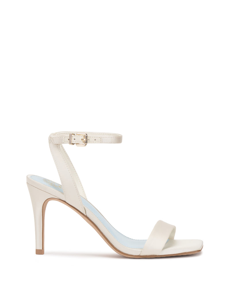 The Saprenda Sandal by Vince Camuto is a single ivory dress sandal with an ankle strap and buckle, open toe, and thin sole on a plain white background.