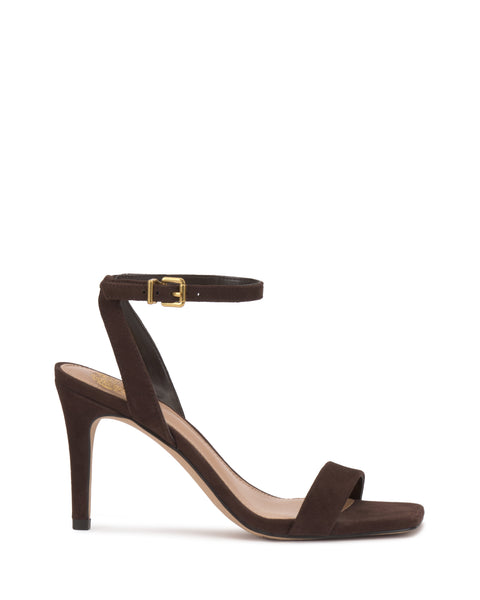 The Saprenda Sandal by Vince Camuto is a dark brown suede stiletto with an open toe, single toe strap, and ankle strap featuring a gold buckle, shown against a white background.